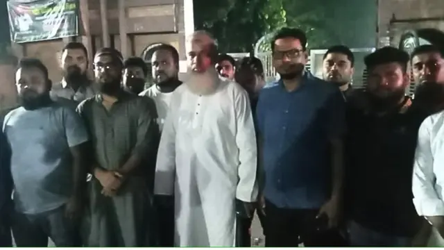 শুক্রবার রাতে জাহাঙ্গীরনগর বিশ্ববিদ্যালয়ের ফটকের সামনে দাঁড়িয়ে জামায়াতে ইসলামীর ঢাকা-১৯ আসনের এমপি প্রার্থী মাওলানা আফজাল হোসাইন (সাদা পাঞ্জাবি পরা)