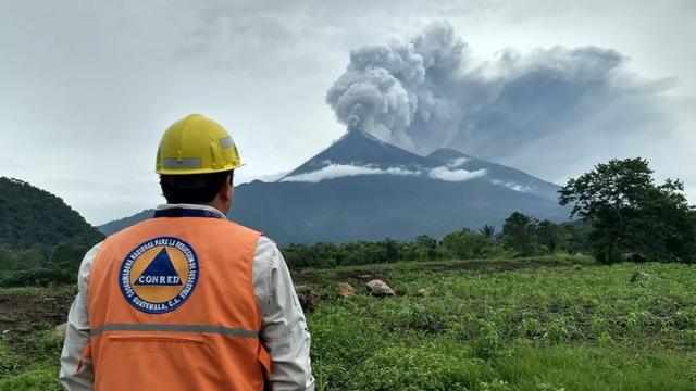 Un empleado de emergencias mira al Volcán de Fuego