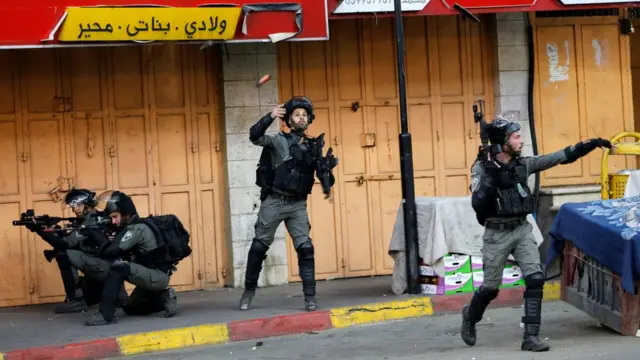A member of Israeli border police hurls a sound grenade towards Palestinians taking part in an anti-Israel protest amid a flare-up of Israeli-Palestinian violence, in Hebron in the Israeli-occupied West Bank May 11, 2021.