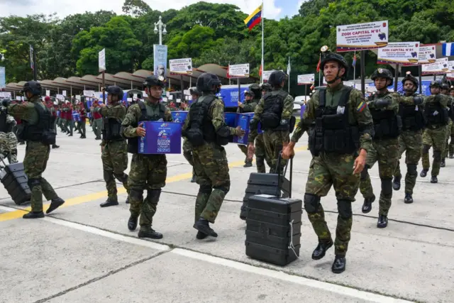 Militares venezolanos con máquinas de votación y urnas.