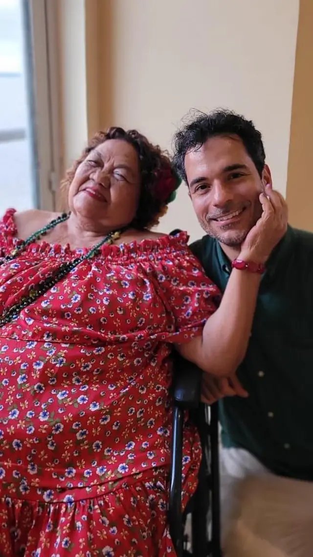 Dona Onete acaricia rosto de repórter enquanto posam para foto