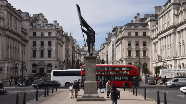 Una estatua que representa a una persona descendiendo de un pedestal con el rostro cubierto por una bandera ondeante en Waterloo Place, el 30 de abril de 2026, en Londres, Inglaterra.