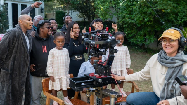Dans les coulisses du tournage de The Polygamist, on aperçoit quelques membres de l'équipe et des acteurs, notamment deux jeunes jumelles debout sur des chaises, vêtues de robes à carreaux assorties, qui sourient pour une photo prise dans un jardin.