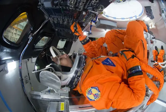 Engenheiros especializados em trajes espaciais demonstram como os quatro tripulantes seriam posicionados para o lançamento dentro da nave espacial Orion.