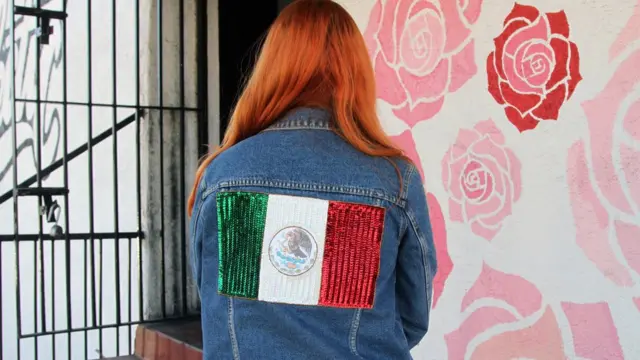 Patty Delgado de espaldas con una chaqueta con la bandera de México