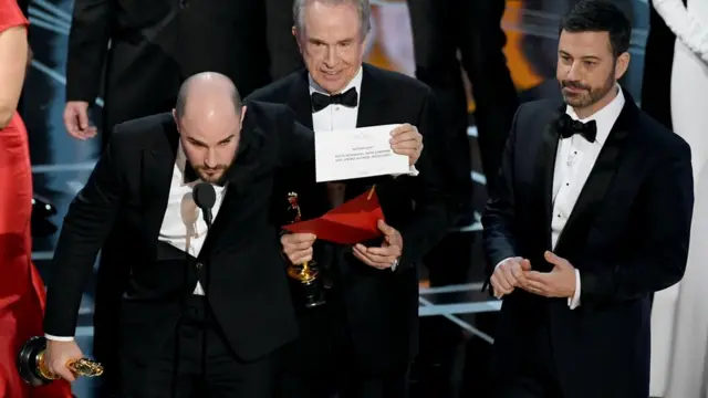 Продюсер "Ла-Ла Ленда" Джордан Хоровиц держит статуэтку "Оскар" и правильный конверт с победителем, рядом стоит Уоррен Битти