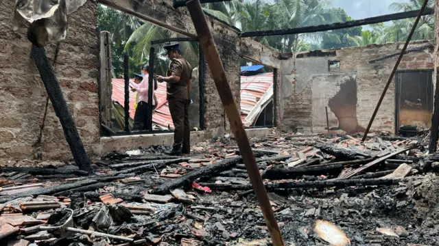 ගින්නට හසුවී විනාශ වූ ස්ථානය තුළ රැඳී සිටින පොලිස් නිලධාරියෙක්