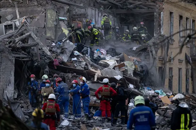Equipes de resgate procuram pessoas sob os escombros de um prédio residencial destruído por um ataque com míssil russo em Kiev (Ucrânia)