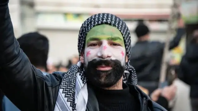 Seorang pengungsi Suriah dengan wajah yang dilukis dengan bendera Suriah di Ankara, Turki.
