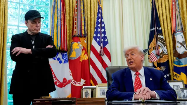 Donald Trump sentado e Elon Musk, de pé, na Casa Branca