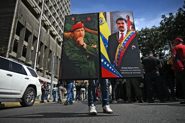 Un chavista sostiene un retrato de Chávez y otro de Maduro