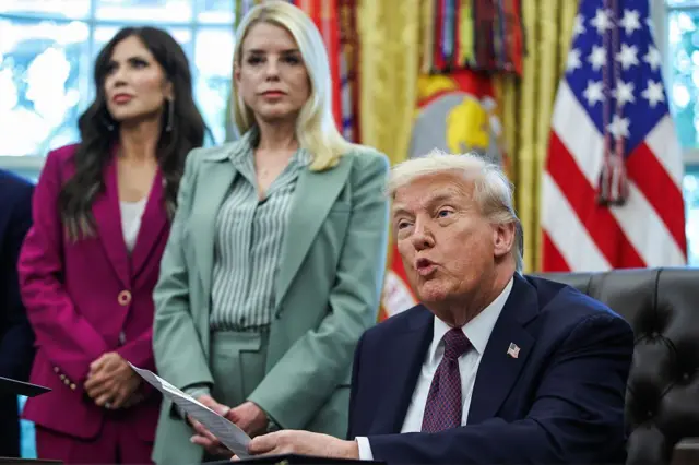 Donald Trump y detrás de Kristi Noem