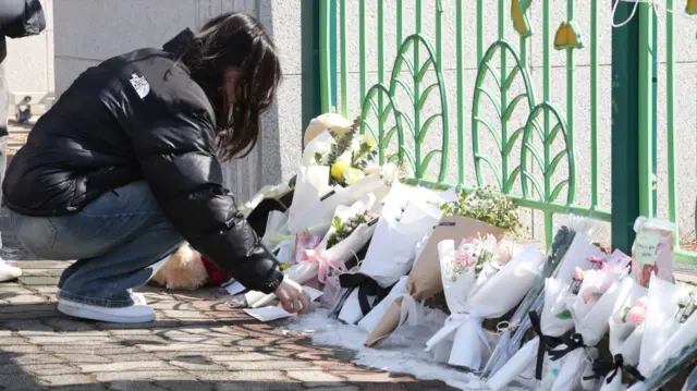 Ciudadanos ofrecen flores frente a la puerta de la escuela primaria A de Daejeon