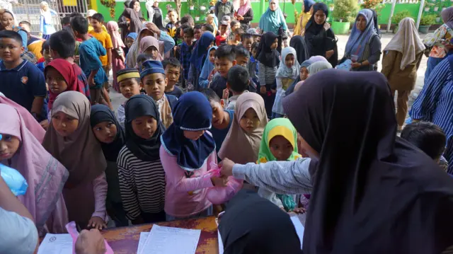 Guru membagikan paket MBG di SD Al Jihad Kota Sorong, Papua Barat Daya, Senin (22/12/2025). Sejumlah sekolah di Papua Barat Daya mulai membagikan paket MBG seminggu sekali berupa buah, roti, susu, kue kering, keripik tempe dan kue basah.