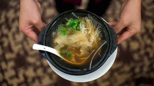 Shark fin soup being held in a bowl