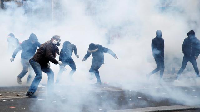 Protesters react amid tear gas during clashes at a demonstration in Paris on 5 December, 2019.