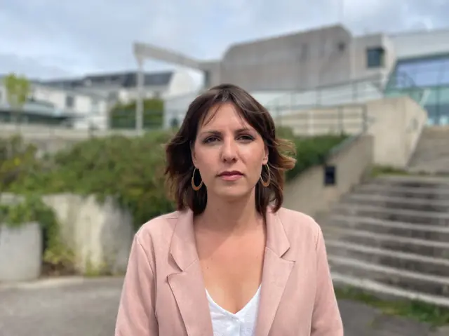Portrait d'une jeune femme aux cheveux bruns portant une veste de costume rose