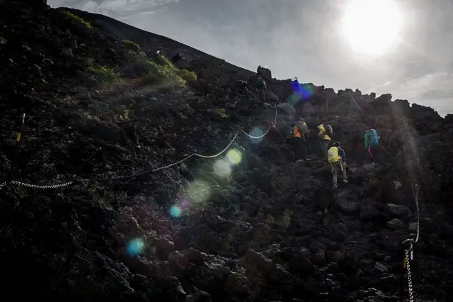 : Climbers hike along a trail to the summit of Mt Fuji