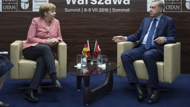 Angela Merkel ile Cumhurbaşkanı Erdoğan Varşova zirvesinde koltukta oturup konuşuyor.