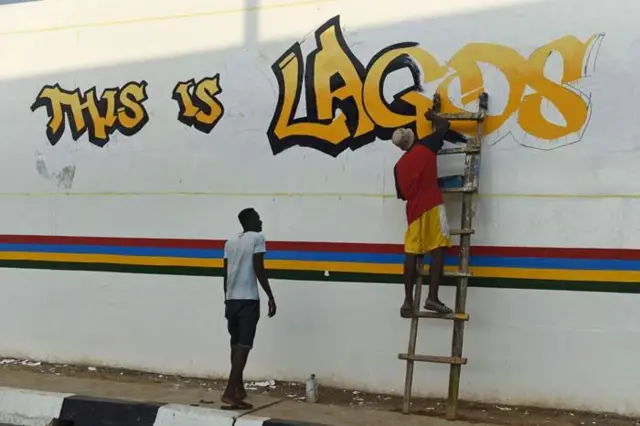 Two men dey paint graffiti for wall