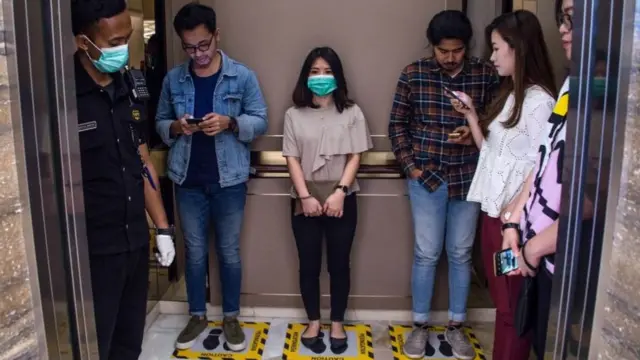 Personas mantienen distanciamiento social en un ascensor en Indonesia