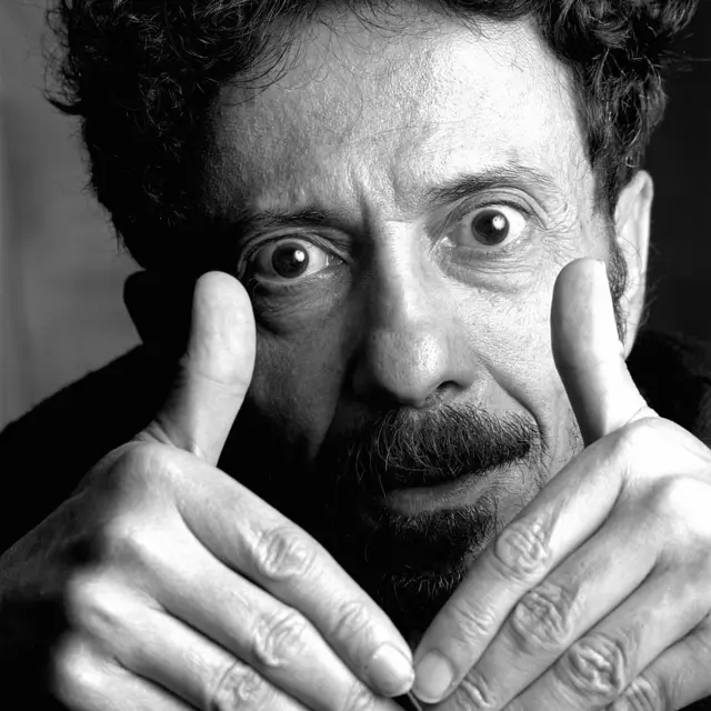 Tom Zé com olhos bem abertos e mãos à frente do rosto, com polegares elevados