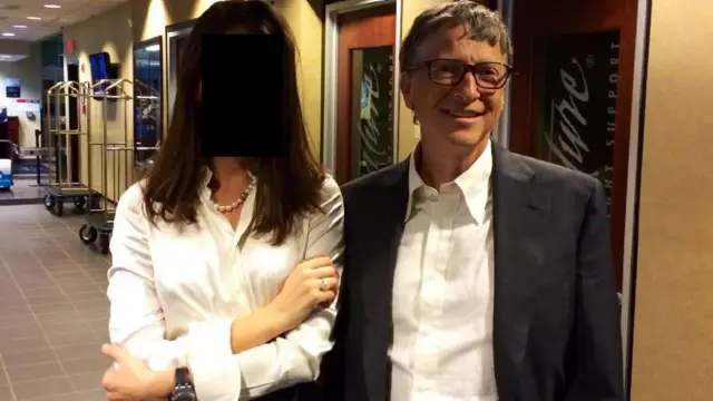 Ông Bill Gates mỉm cười và đứng cạnh một phụ nữ có khuôn mặt đã bị che 