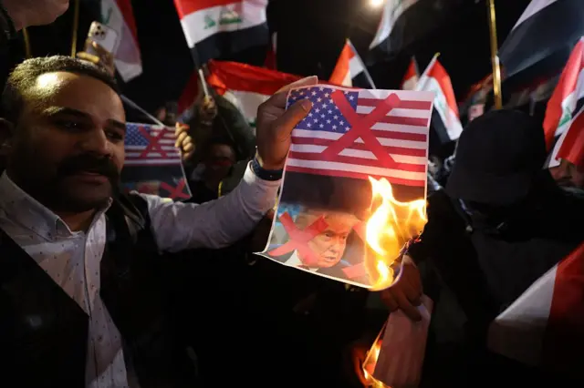 گروهی از معترضان در حال آتش زدن تصویر پرچم آمریکا و دونالد ترامپ در خیابان