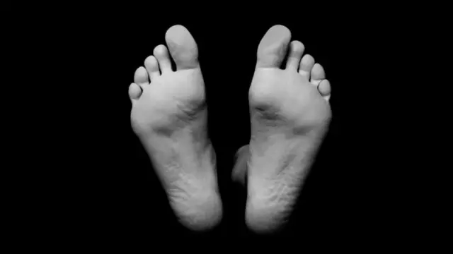 মরদেহের প্রতীকী ছবিতে এক ব্যক্তির পা দেখা যাচ্ছে