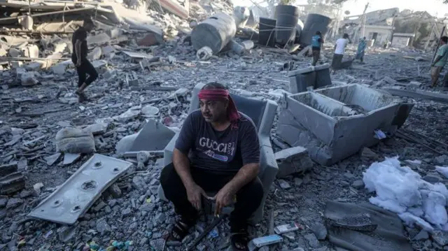 घर के मलबे पर बैठा अल ज़हरा का एक निवासी