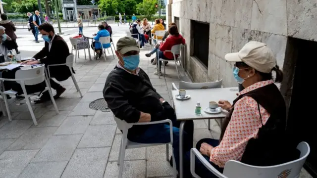 Pessoas com máscara tomando café