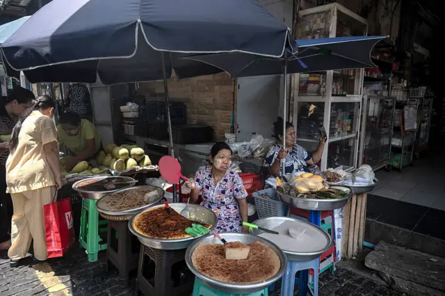 ၂၀၂၆ ခုနှစ်၊ ဇွန်လထဲ ရန်ကုန်မြို့၊ ဗိုလ်ချုပ်ဈေးထဲမှာ ဝယ်သူမျှော်နေတဲ့ မြန်မာမုန့်ရောင်းချတဲ့ဈေးသည်တွေကိုတွေ့ရစဉ် 
