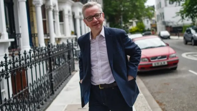 Michael Gove posa para foto, na rua