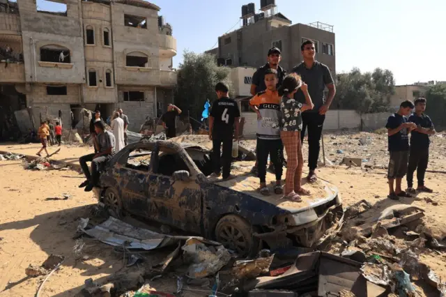 গাজা ভূখণ্ডের রাফা-এ ইসরায়েলের হানার পর বিধ্বংস একটি গাড়িতে দাঁড়িয়ে উদ্ধারকাজ দেখছেন ফিলিস্তিনিরা 