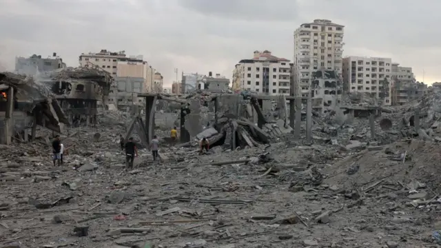 Palestinians inspect the destruction following Israeli airstrikes on Gaza City's al-Rimal district, early on October 10, 2023