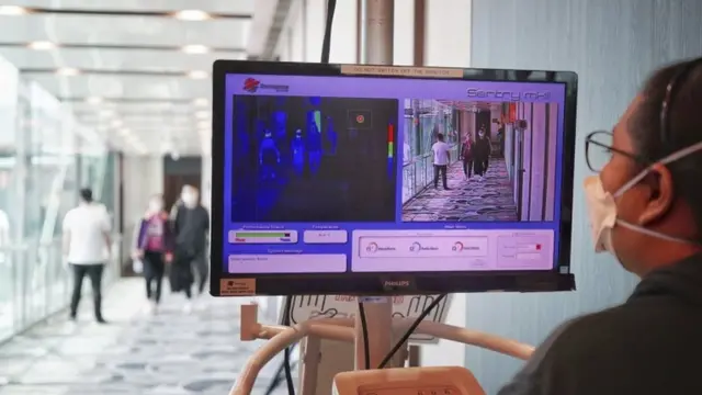 সিঙ্গাপুর বিমানবন্দরে পৌছানোর পর সেখানে যাত্রীদের শরীরের তাপমাত্রা মেপে দেখা হচ্ছে।