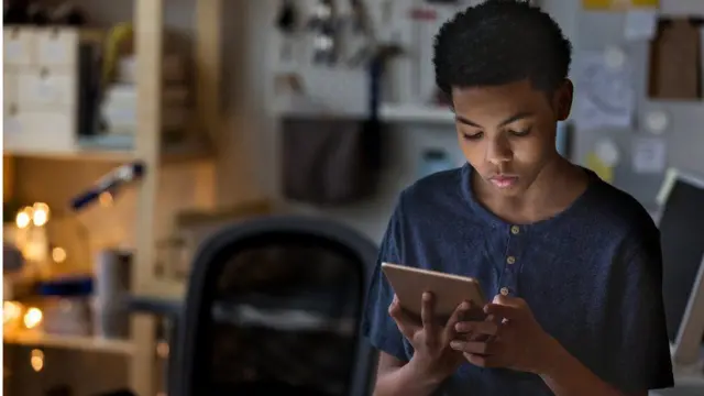 ሞባይል የሚመለከት ታዳጊ