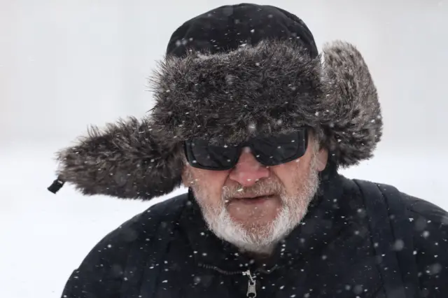 Седой бородатый мужчина в ушанке и солнечных очках