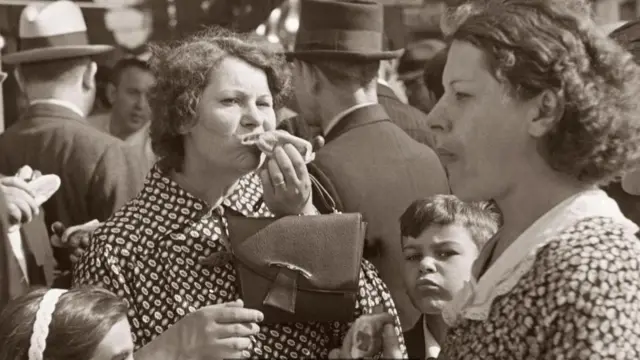 Una mujer comiendo perros calientes