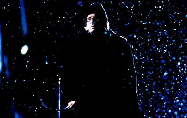 Un homme debout sous la neigne et dans le noir.