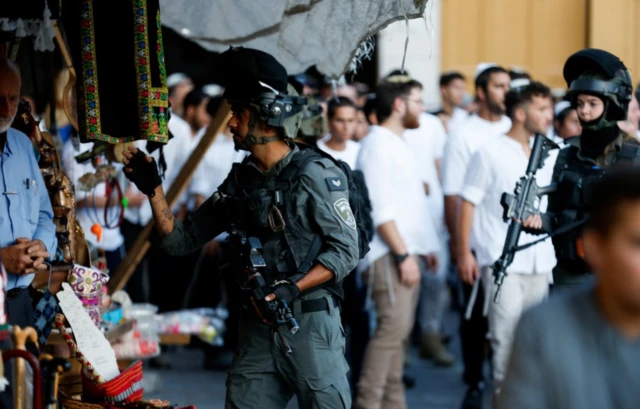 ضابط شرطة حدود إسرائيلي يأمر صاحب متجر فلسطيني بالدخول إلى متجره خلال جولة أسبوعية للمستوطنين في الخليل، في الضفة الغربية المحتلة