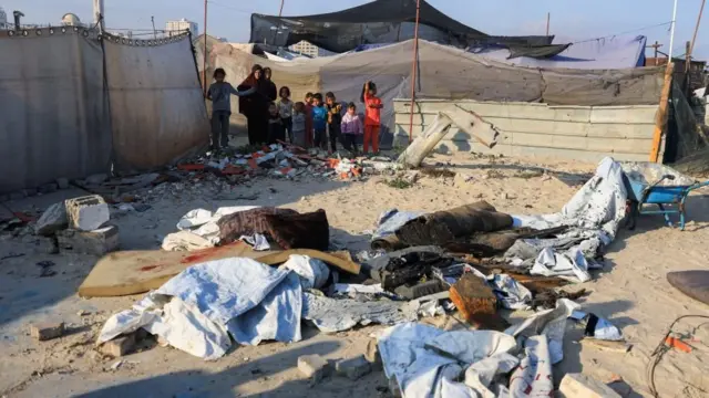 Palestinians inspect the damage at the site of an Israeli airstrike on a tent sheltering displaced people at the Gaza seaport, in Gaza City,