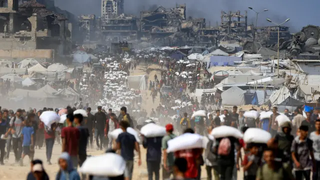 فلسطينيون يتجمعون وهم يحملون إمدادات المساعدات التي دخلت غزة عبر إسرائيل، وسط أزمة الجوع، في بيت لاهيا في شمال قطاع غزة.