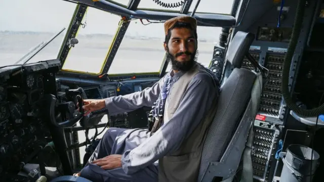 এক পরিত্যক্ত মার্কিন বিমানের ককপিটে বসে আছেন এক তালেবান যোদ্ধা।