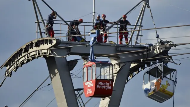 Firefighters assess the damage caused after a cable car struck a pillar in Cologne, Germany, 30 July 2017