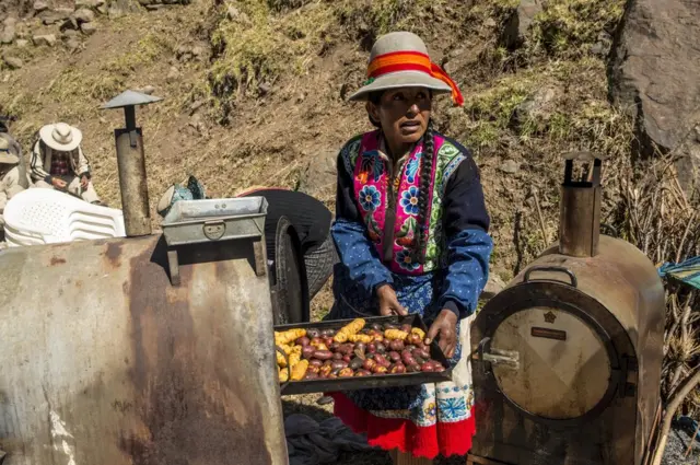 Uma mulher cozinha batatas, servidas como acompanhamento dos pratos principais