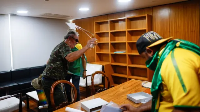 Homens com roupas militares e camisetas do Brasil vandalizam sala do planalto