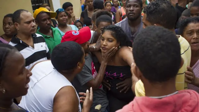 Los vecinos del barrio de Capotillo intentan consolar a la madre de las niñas que murieron cuando un desplazamiento de tierra impactó las paredes de su casa durante el paso del huracán Matthew.