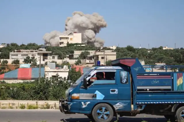 أعمدة دخان تتصاعد من أحد المباني إثر قصف جوي روسي لمدينة إدلب شمالي سوريا