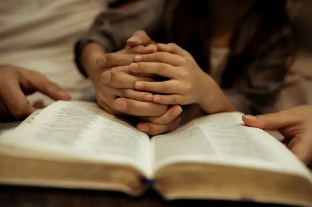 Un padre enseñando a una niña a orar